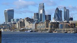The London City skyline contrasts with warehouses and moored sailing barges on the waterfront in Wapping. Viewed from Bermondsey. UK
