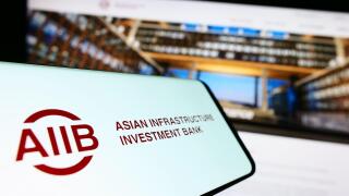 Smartphone with logo of Asian Infrastructure Investment Bank (AIIB) on screen in front of website. Focus on center-left of phone display.