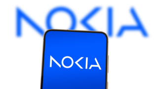 Nokia company logo displayed on smartphone in front of Nokia's logo blurred out behind it on a white background