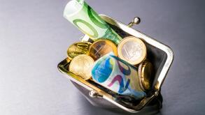 Wallet filled with many euro coins and banknotes