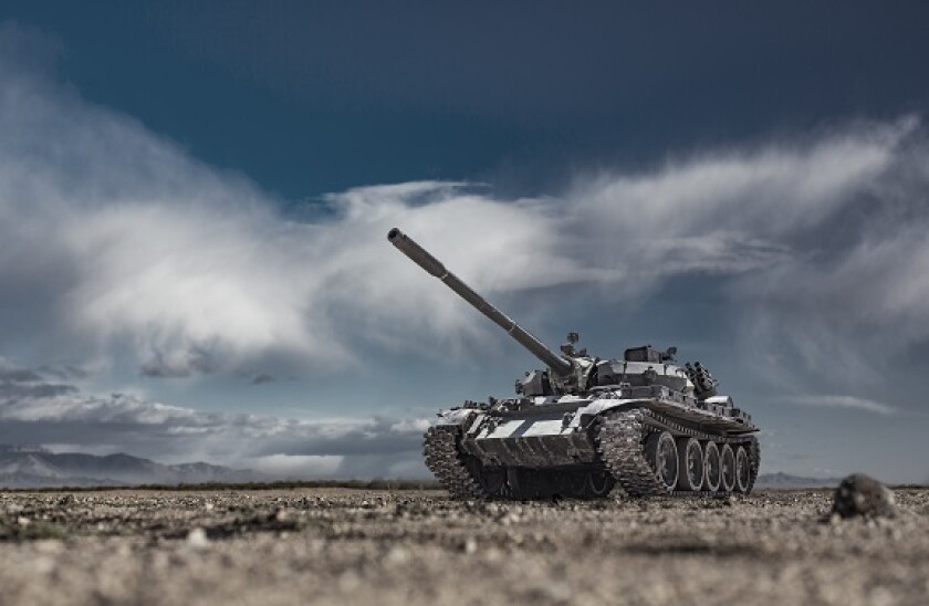 Military or army tank ready to attack moving over a deserted battle field terrain