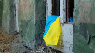 A destroyed building and a broken door from the explosion and next to it lies the flag of Ukraine in the city of Dnepr in Ukraine, war