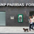 Couple walking past ATM cash dispenser at cashpoint of the BNP Paribas Fortis bank