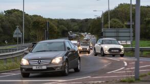 Cars with lights on in traffic being driven to work in the early morning rush hour, on the A27 road in the UK.