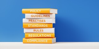 Books of Compliance And Regulations In Front Grey Wall