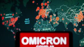 In this photo illustration, a phone screen shows a text that says Omicron COVID-19.