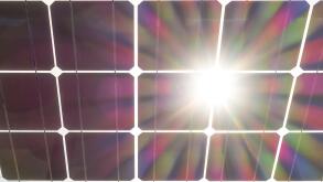 Solar panels wit sun burst flare. Solar panel seen from behind, underneath. Solar cells on clear glass with sun shining through.