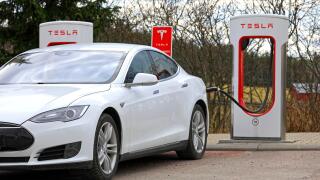 White Tesla Model S electric car connected and charging at Supercharger station on a day of spring in Paimio, Finland - April 28, 2018.