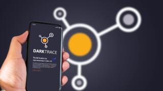 Cambridge, UK, May 2021: A hand holding a phone with the Darktrace company logo on the screen. Darktrace is an AI company that specialises in cyber de