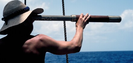 A young man with a long telescope is literally "looking to the future" as he scans the sea from the deck of an old sailing ship in the Caribbean Sea.. Image shot 2009. Exact date unknown.
