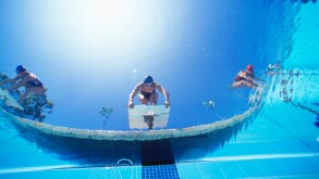 Low ngle view of female swimmers ready dive in pool from starting position