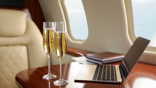 Glasses of champagne with laptop and notebooks on table in airplane-adobe