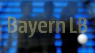 Employees of the Bavarian public sector bank BayernLB are silhouetted as they walk near the bank's logo at the BayernLB headquarters in Munich July 2, 2012.   REUTERS/Michaela Rehle/File Photo