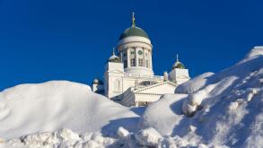 Helsinki, Finland - February 6, 2019: Helsinki Cathedral behind huge pile of snow on a sunny and cold winter afternoon after weeks of heavy snowfall