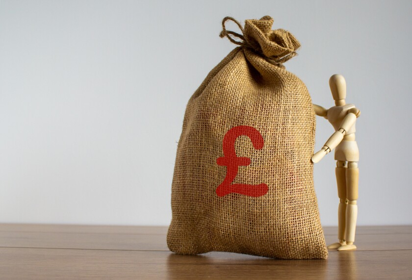 Wooden model of a man near large canvas bag with a pound sterling sign.