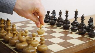 Man's hand making first move in chess game. E2-E4 move. White starts the game.