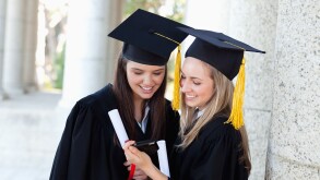 Smiling graduating students looking at a digital camera while standing upright