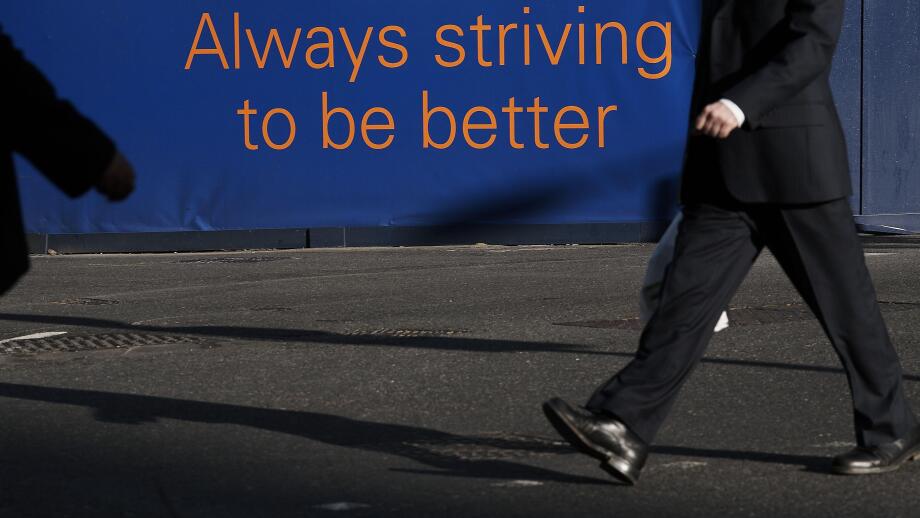GREAT BRITAIN / England /Canary Wharf/ Banker in Canary Wharf with sign Always striving to be better.