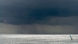 One surfer out at sea with a storm approaching, near Pointe aux Piments, Mauritius, Africa, Indian Ocean