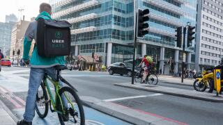 An Uber Eats delivery cyclist outside Uber Headquarters in Aldgate Tower, Whitechapel, London, UK