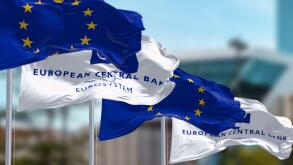 Frankfurt, DE, March 2023: Three Flags of the European Central Bank and European Union waving in the wind with the ECB seat blurred on background. Ill