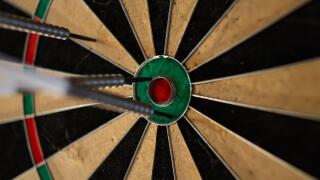 Darts in a dartboard close up. The bullseye is the target but it was missed. The objective is to hit the center. This leisure activity is a party game