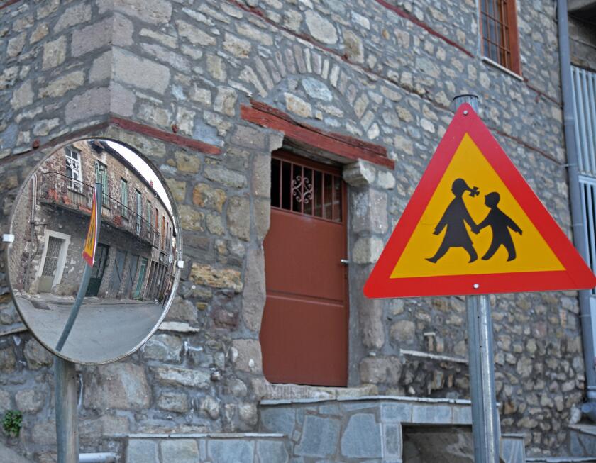 Traffic sign, warning people to be careful of people crossing the street as seen in a traffic mirror at the village of Kanalia, Karditsa, Greece.