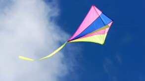 a kite flying against a blue sky in sunlight bright colors and streaming tail. Image shot 2007. Exact date unknown.