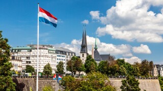 View over the Petrusse Valley Park to the Grand Hotel Cravat and Notre-Dame Cathedral. Luxembourg flag flies against a blue sky.