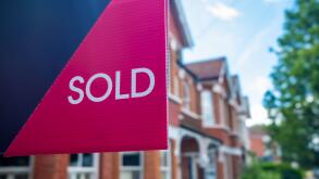 Estate agent 'SOLD' sign on residential street