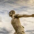White stone statue of a man running in the clouds