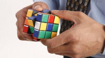 Businessman hand holding Rubik cube in both hands and trying to solve puzzle Model Release # 703T