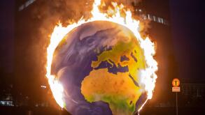 21 October 2020, Hessen, Frankfurt/Main: With a burning globe, activists of the group "Das Koalakollektiv" demonstrate in front of the European Central Bank (ECB) in Frankfurt against the climate policy of the financial institution. The activists demand t