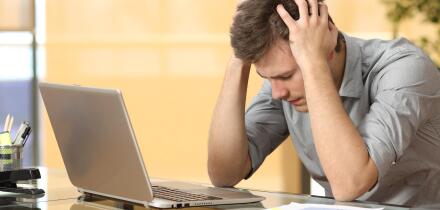 Worried businessman lamenting in front of a computer after a big mistake at office