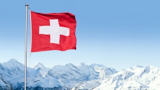 The flag of Switzerland fluttering in the wind with the Bernese Alps in the background, Grindelwald, Switzerland.