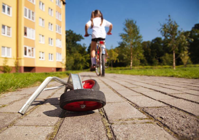 Girl on bicycle leaving her training wheels behind