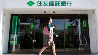 A woman walks past a branch of Sumitomo Trust and Banking Co in Tokyo November 6, 2009. Sumitomo Trust and Banking Co and Chuo Mitsui Trust Holdings Inc said they plan to merge, creating Japan's largest trust bank with scale to better compete in a crowded