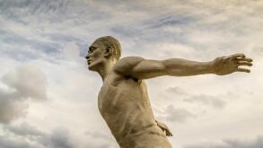 White stone statue of a man running in the clouds