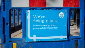 A sign next to a hole in the ground from Thames Water supply company stating "We're fixing pipes so we can always bring you world-class water". London
