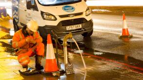 watermain burst repaired by Thames water engineer at road side, England