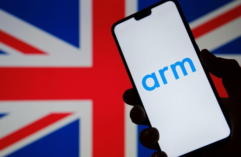 ARM Holdings logo seen on the silhouette of smartphone hold in hand and the United Kingdom flag on a blurred background