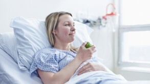 Patient lying in hospital bed eating apple