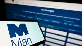 Mobile phone with logo of British financial company Man Group plc on screen in front of business website. Focus on left of phone display.