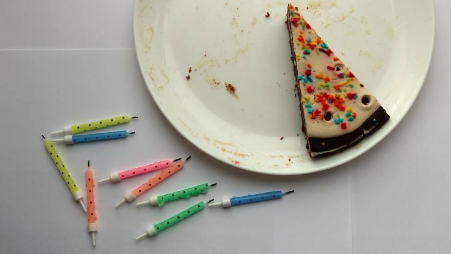 conceptual background on the theme of loneliness and the end of the holiday, top view of the last piece of birthday cake on a white dirty plate