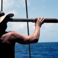 A young man with a long telescope is literally "looking to the future" as he scans the sea from the deck of an old sailing ship in the Caribbean Sea.. Image shot 2009. Exact date unknown.