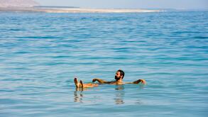 DEAD SEA; ISRAEL - 16 OCTOBER, 2014: A man floating in the salty water of the dead sea in Israel