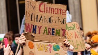 Homemade sign at environmental rally. A colorful cardboard placard is viewed close up, saying the climate is changing, why aren't we, in the hands of ecological activists as they protest in the city