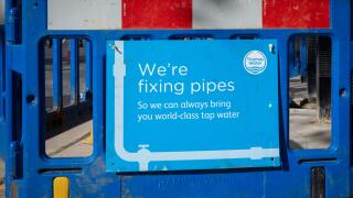 A sign next to a hole in the ground from Thames Water supply company stating "We're fixing pipes so we can always bring you world-class water". London