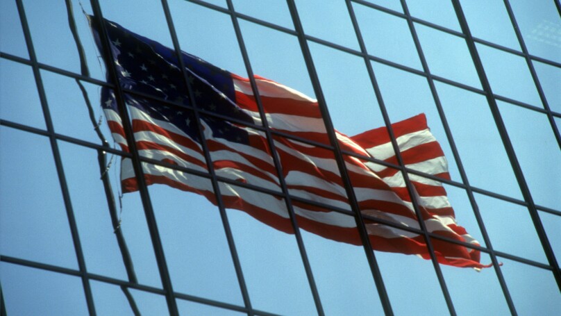 American flag reflected in a glass office building