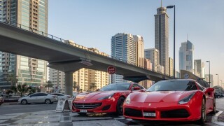 2 red Ferrari's parked near the Sheikh Zayed Road, with the metro line close by Dubai, United Arab Emirates (UAE).